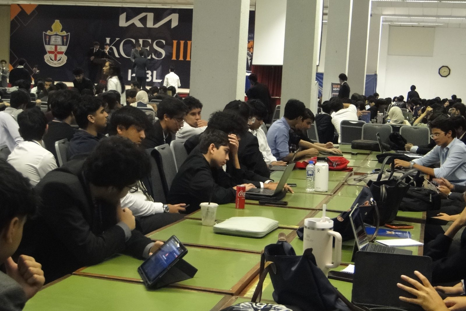 Delegates working on laptops in the main hall at KGES III